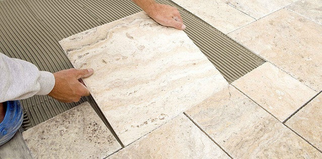 handyman applying ceramic tiles on the floor