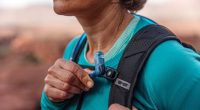 Close-up of a hiker's torso holding a water hose from a hydration pack.