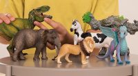 schleich toys on a table with a kid in yellow behind them